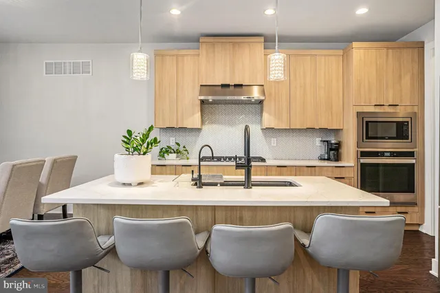 a kitchen with stainless steel appliances granite countertop a kitchen island a stove a table and chairs