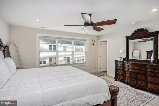 a bedroom with a bed a dresser and a large window