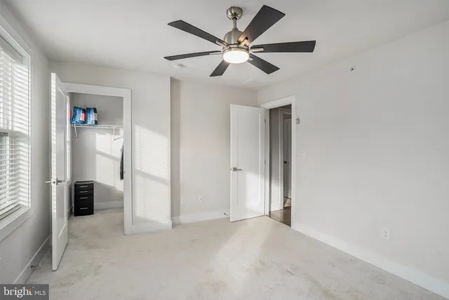 an empty room with closet and a ceiling fan