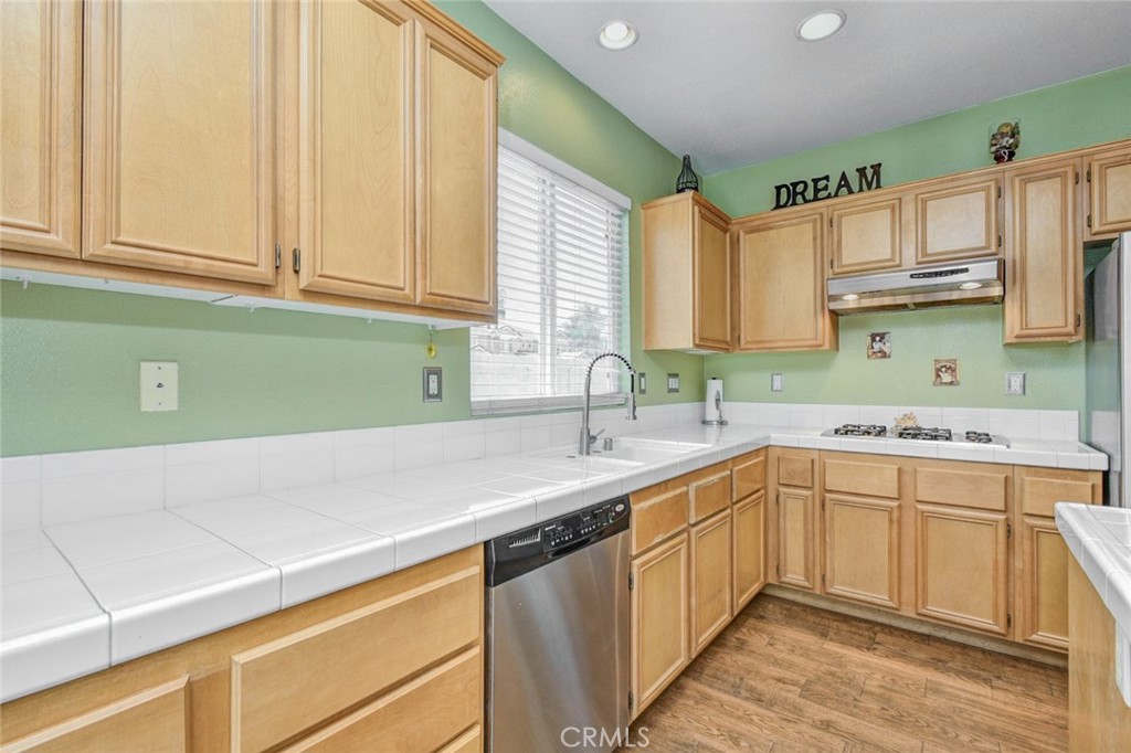 6174 Risingstar Drive Eastvale, CA 92880 - Photo 14 of 57 a kitchen with a sink dishwasher a stove and white cabinets with wooden floor
