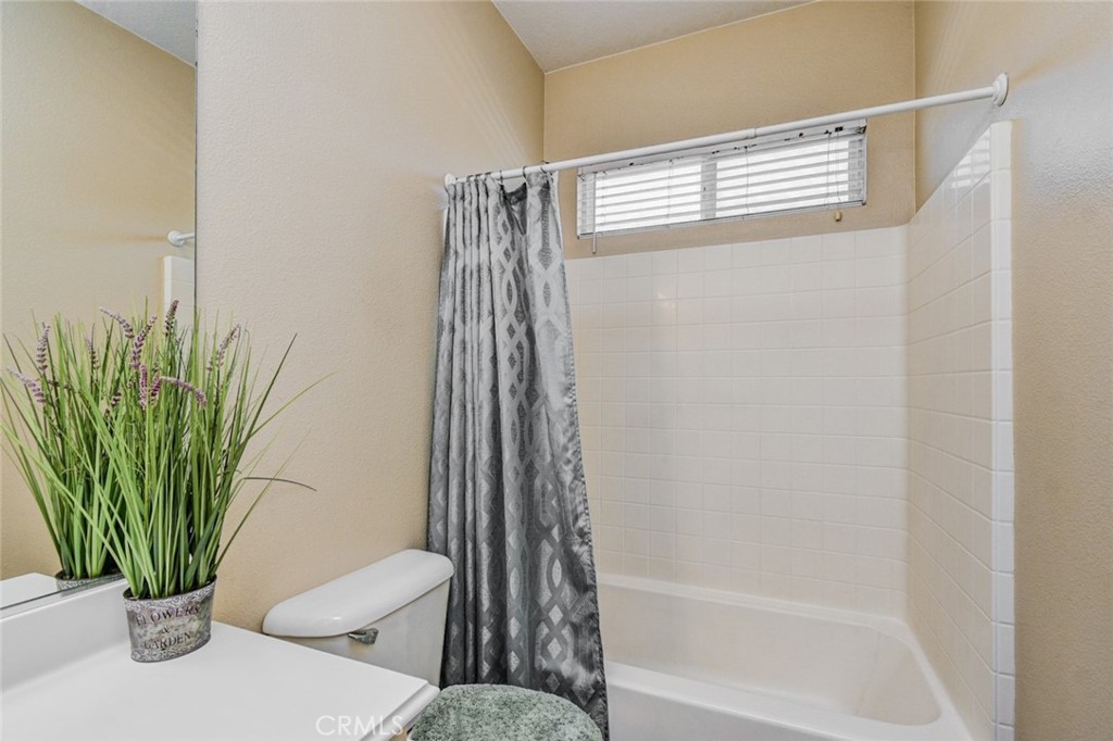 6174 Risingstar Drive Eastvale, CA 92880 - Photo 38 of 57 a bathroom with a shower curtain and a window