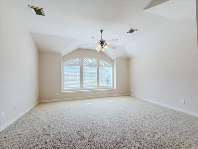 an empty room with chandelier fan and windows