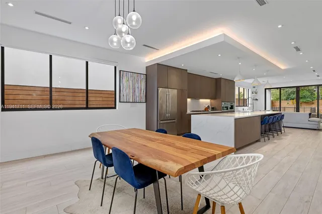 a kitchen with stainless steel appliances kitchen island granite countertop a table chairs in it and wooden floors