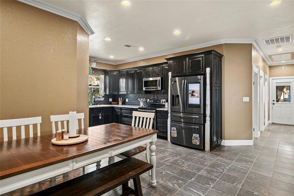 202 North Kickapoo Street Lipan, TX 76462 - Photo 6 of 38 Kitchen featuring dark wood cabinetry, stainless steel appliances, and a subway tile backsplash