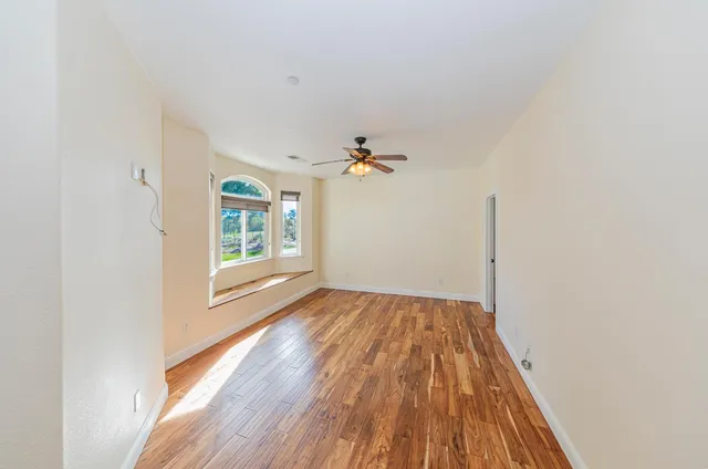 a view of an empty room with wooden floor and a window