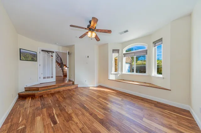 a view of empty room with wooden floor and fan