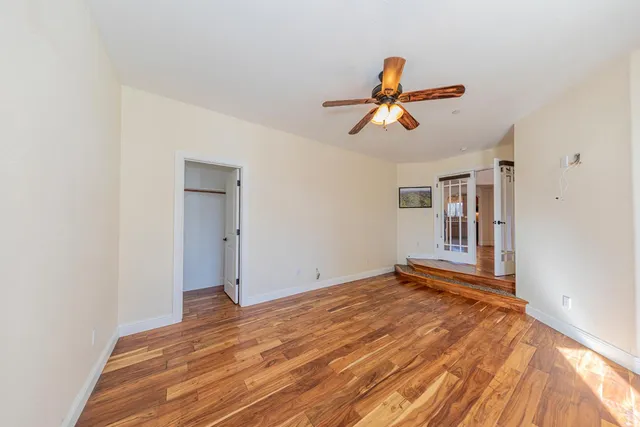 a view of an empty room with window and wooden floor