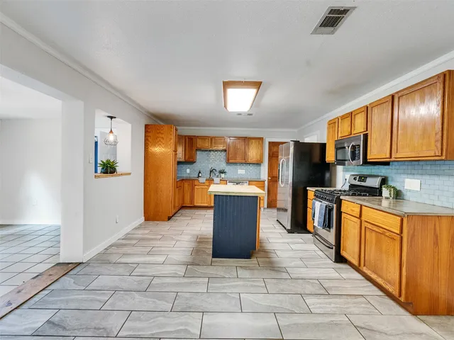 a large kitchen with stainless steel appliances kitchen island granite countertop a refrigerator and cabinets