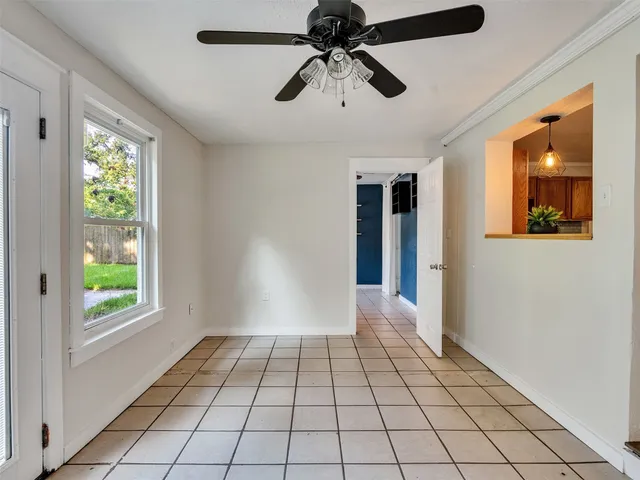 a view of an empty room with window and chandelier fan