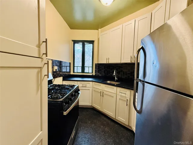 a kitchen with stainless steel appliances granite countertop a refrigerator a sink and white cabinets