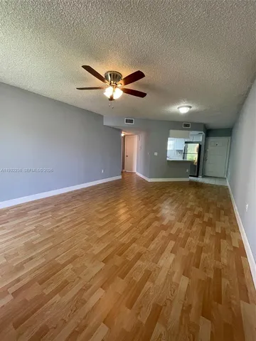 a view of an empty room with window and chandelier fan