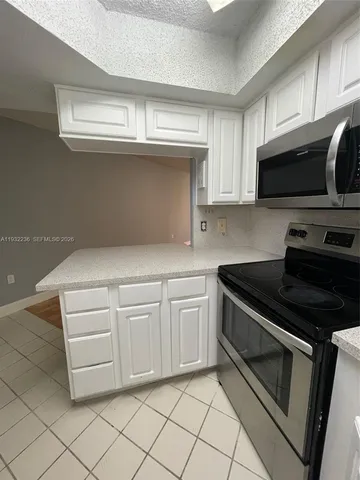 a kitchen with granite countertop white cabinets and black appliances