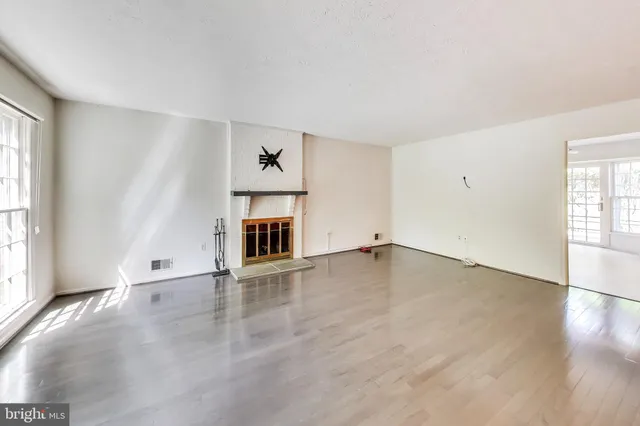 a view of an empty room with wooden floor and a ceiling fan
