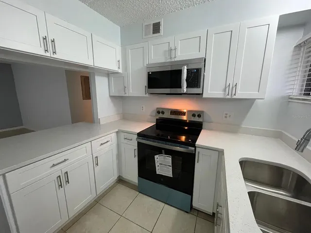 a kitchen with white cabinets and black appliances