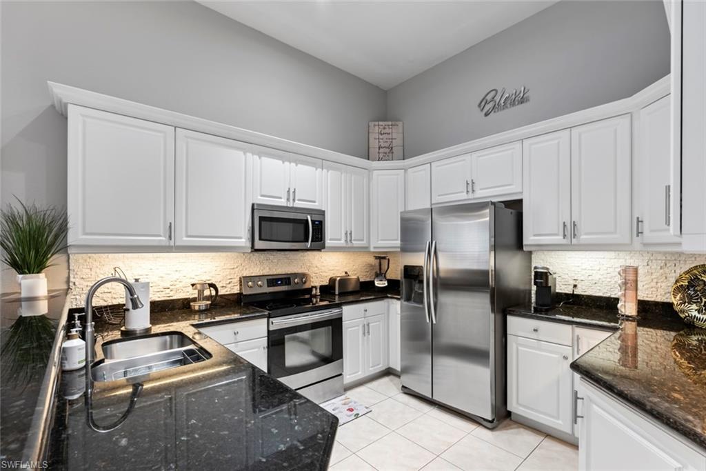 6051 Shallows Way Naples, FL 34109 - Photo 14 of 38 a kitchen with a refrigerator stove and white cabinets