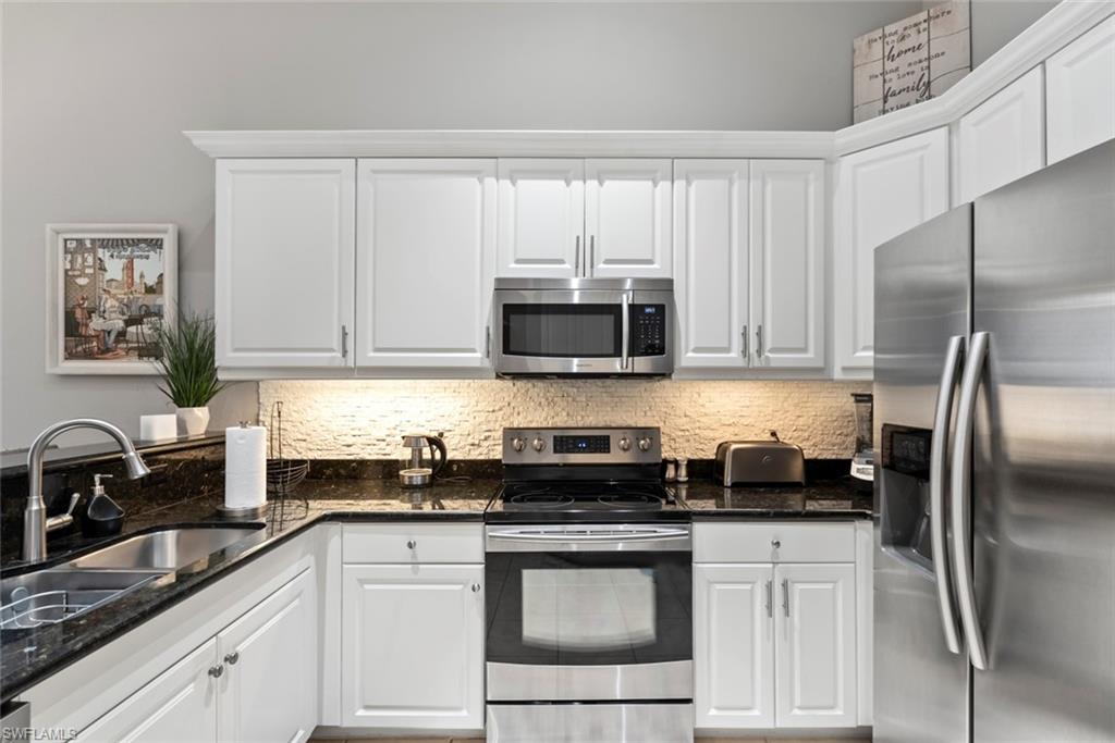 6051 Shallows Way Naples, FL 34109 - Photo 17 of 38 a kitchen with granite countertop white cabinets and stainless steel appliances