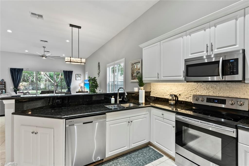 6051 Shallows Way Naples, FL 34109 - Photo 18 of 38 a kitchen with stainless steel appliances granite countertop a sink a stove a microwave and cabinets