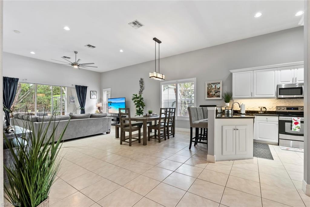 6051 Shallows Way Naples, FL 34109 - Photo 6 of 38 a kitchen with stainless steel appliances granite countertop a refrigerator a stove top oven a sink a dining table and chairs