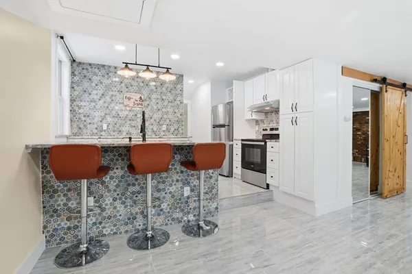 a kitchen with stainless steel appliances kitchen island granite countertop a refrigerator and a stove top oven