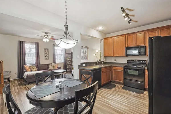 a kitchen with stainless steel appliances granite countertop a stove a sink dishwasher a dining table and chairs with wooden floor