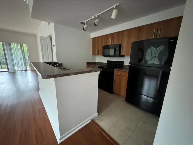 a kitchen with stainless steel appliances granite countertop a refrigerator a stove top oven a sink and dishwasher