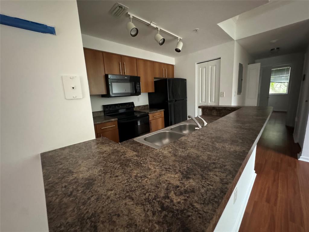 5800 West Sample Road, Unit 2011 Coral Springs, FL 33067 - Photo 15 of 25 a kitchen with granite countertop a stove a microwave a refrigerator a sink and dishwasher with wooden floor