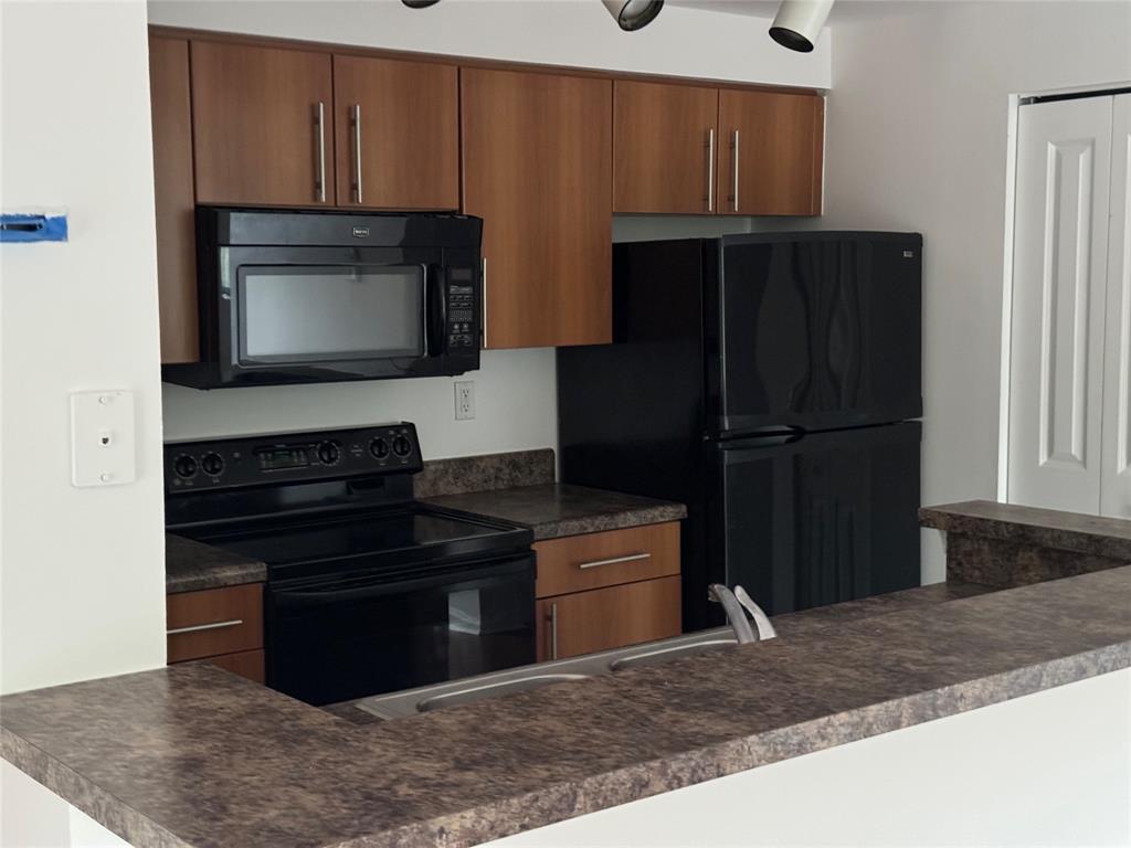5800 West Sample Road, Unit 2011 Coral Springs, FL 33067 - Photo 17 of 25 a kitchen with wooden cabinets and a refrigerator