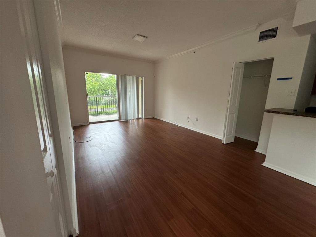 5800 West Sample Road, Unit 2011 Coral Springs, FL 33067 - Photo 9 of 25 an empty room with wooden floor and windows