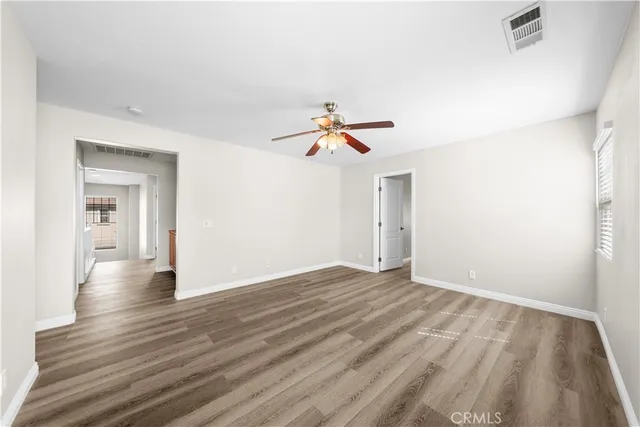 a view of empty room with wooden floor and ceiling fan