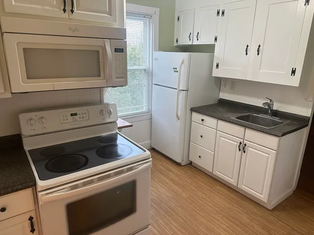 a kitchen with white cabinets and white appliances