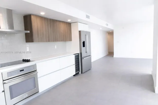 a kitchen with stainless steel appliances white cabinets and a refrigerator