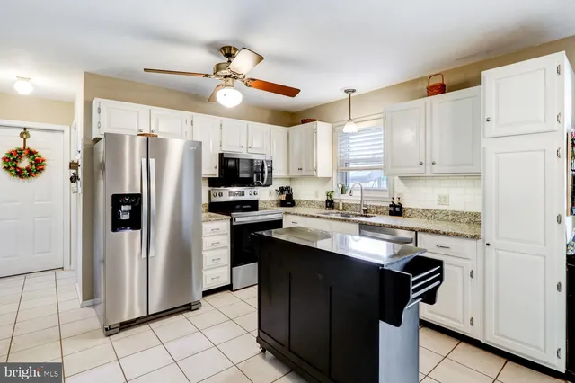 a kitchen with stainless steel appliances granite countertop a refrigerator a stove a sink and white cabinets