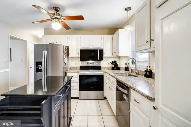 a kitchen with stainless steel appliances granite countertop a refrigerator a stove a sink and a microwave