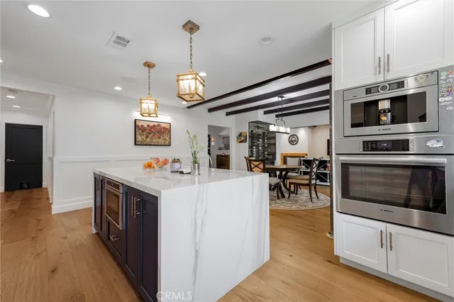 a kitchen with stainless steel appliances kitchen island granite countertop a stove and a wooden floor