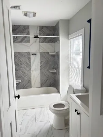 a bathroom with a bathtub shower sink vanity and toilet