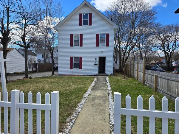 a view of a white house next to a road and yard
