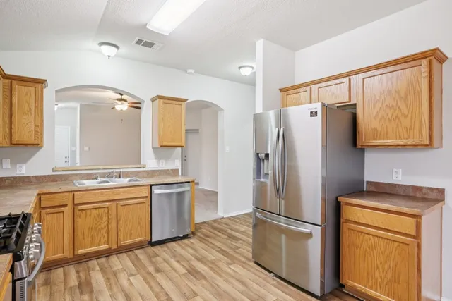 a kitchen with a refrigerator a sink and dishwasher a stove top oven with wooden floor