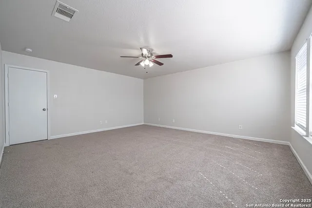 an empty room with a window and a ceiling fan
