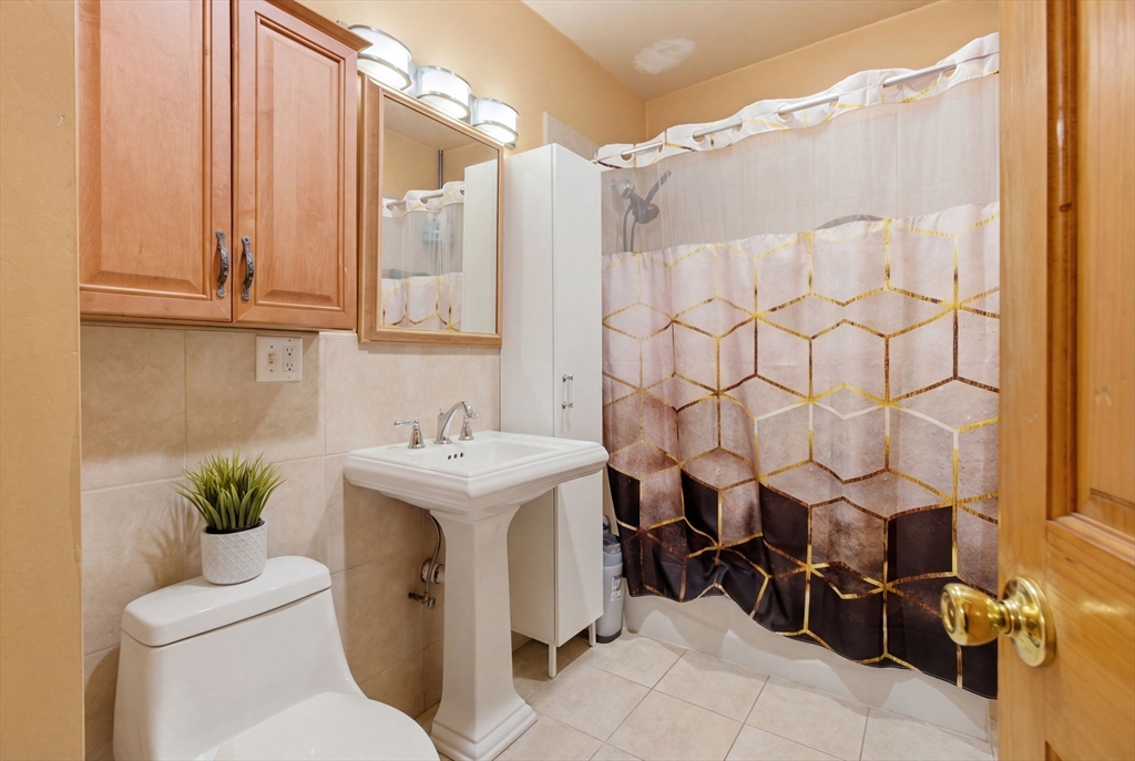 22 Deering Road, Unit 1 Boston, MA 02126 - Photo 11 of 12 a bathroom with a sink a toilet and shower curtain