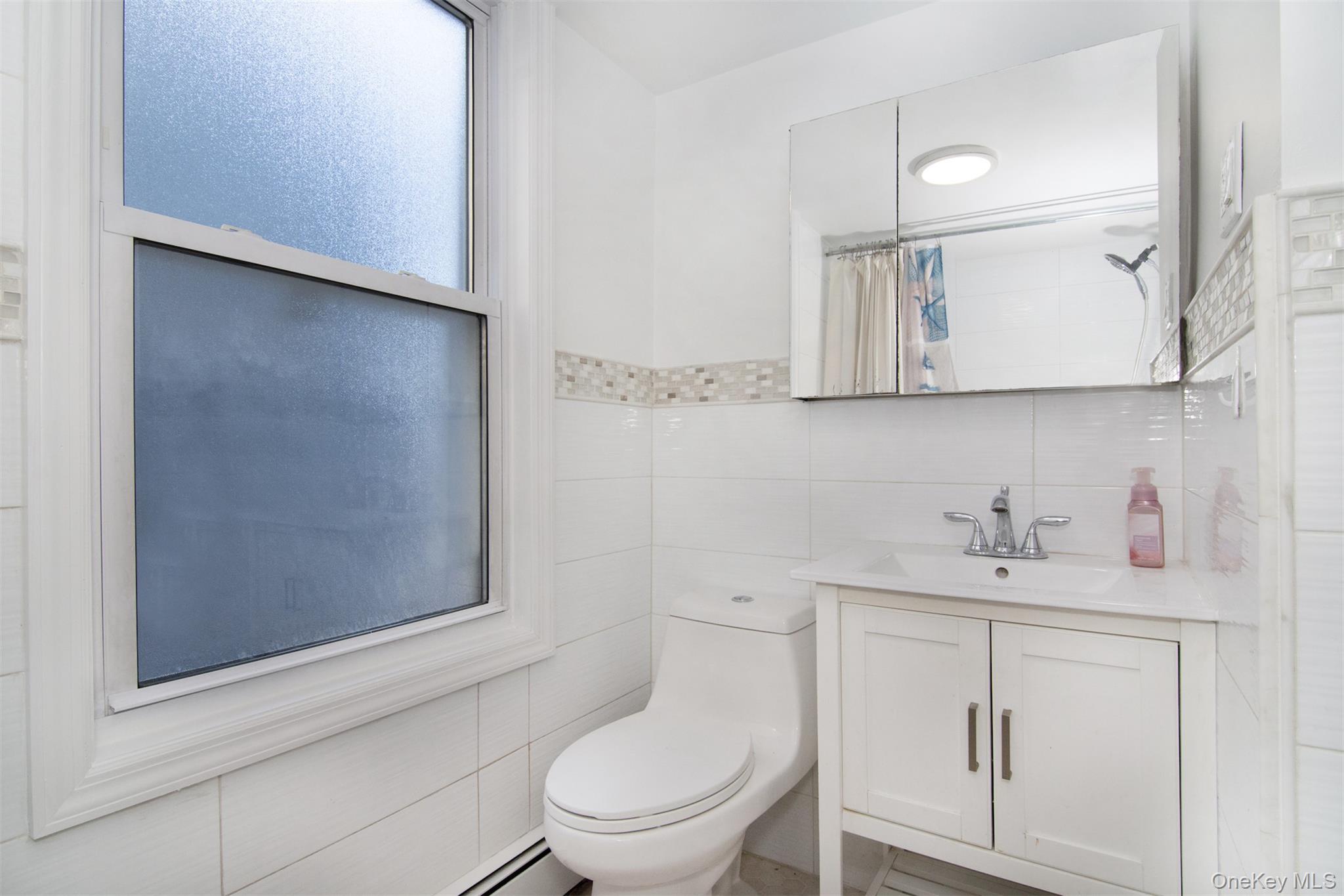 44 Ridge Street, Unit 1 Hastings-on-Hudson, NY 10706 - Photo 9 of 16 Bathroom featuring tile walls, toilet, walk in shower, decorative backsplash, and vanity