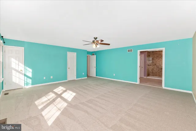 an empty room with windows and fan