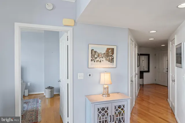 a view of a hallway with wooden floor and a bathroom