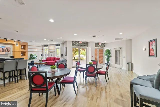 a living room with furniture a dining table wooden floor and kitchen view