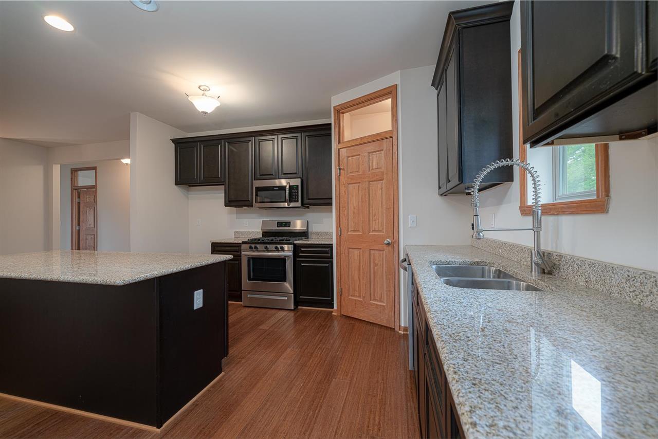 9909 Lismore Road Roscoe, IL 61073 - Photo 11 of 24 a kitchen with kitchen island granite countertop stainless steel appliances and wooden cabinets