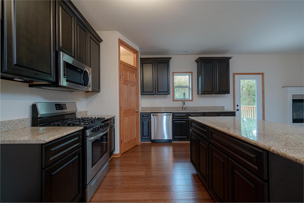 9909 Lismore Road Roscoe, IL 61073 - Photo 10 of 24 a kitchen with stainless steel appliances wooden cabinets stove and microwave