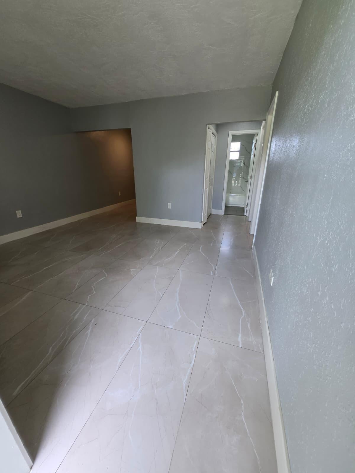 1015 Southwest 8th Street, Unit 1 Miami, FL 33130 - Photo 2 of 7 a view of an empty room with wooden floor and a window