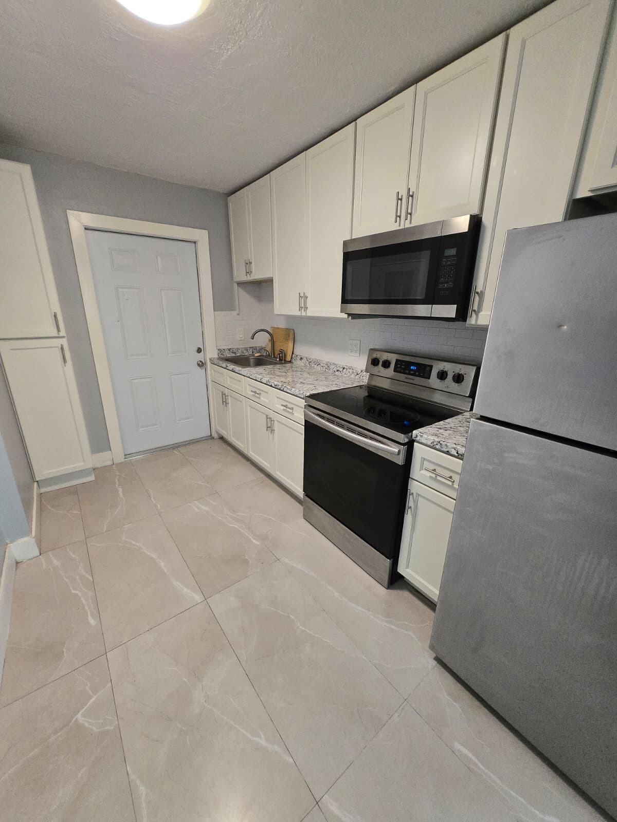 1015 Southwest 8th Street, Unit 1 Miami, FL 33130 - Photo 3 of 7 a kitchen with stainless steel appliances granite countertop a stove a sink and a refrigerator