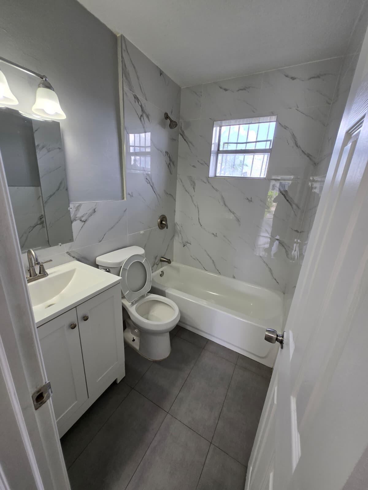 1015 Southwest 8th Street, Unit 1 Miami, FL 33130 - Photo 7 of 7 a bathroom with a granite countertop toilet a sink and bathtub