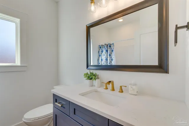 a bathroom with a granite countertop sink vanity mirror and toilet