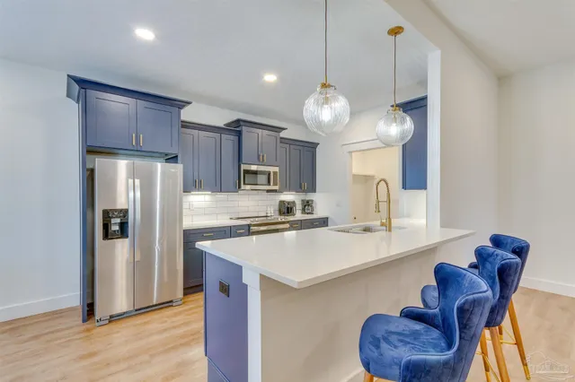 a kitchen with stainless steel appliances granite countertop a refrigerator a stove a sink dishwasher and a refrigerator with wooden floor